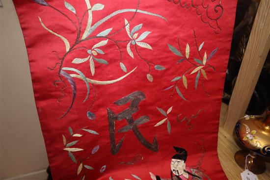 A Chinese red silk banner embroidered with figures, flowers, insects and calligraphy,